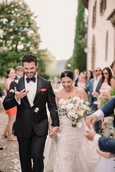 The couple laughing together surrounded by guests and Tuscan sunshine.