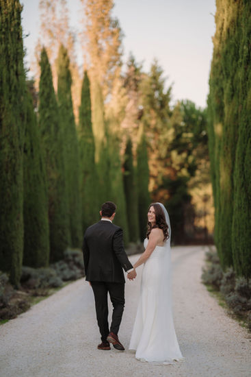 Bride turning back with a smile along the tree lined avenue