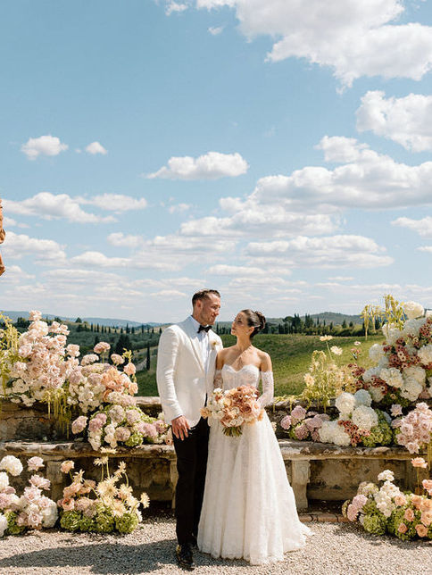 bride and groom portrait with floral arrangements overlooking Tuscan landscape