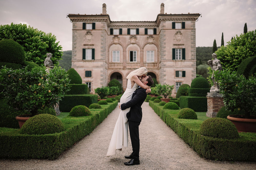 Groom dipping bride in front of Villa Cetinale facade, romantic wedding portrait Tuscany