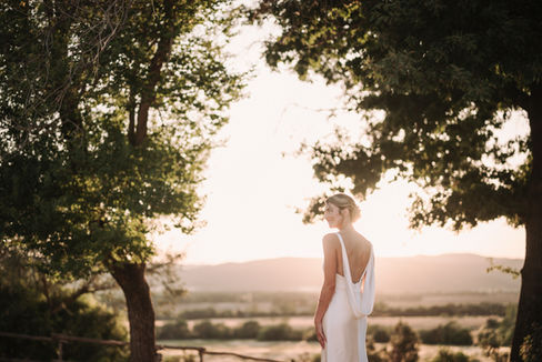 Bride in white dress, looking away, elegant wedding at Conti di San Bonifacio, sunset backdrop. riccardopieri