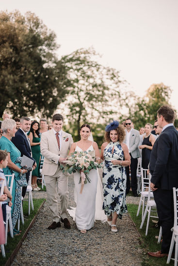 Bride walking down the aisle, arm-in-arm with a man, followed by guests.