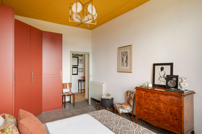 Camera da letto moderna con soffitto giallo e armadio rosso.