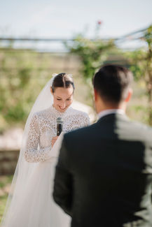 Bride smiling, holding microphone, looking at groom; wedding at Vignamaggio; riccardopieri