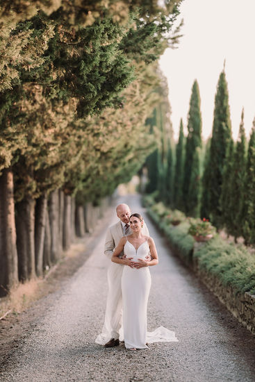 Bride and groom posing on the tree-lined lane.