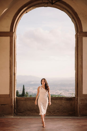 Woman walks toward camera through archway; Alyssa and Sean elopement at Belmond Villa San Michele Florence.