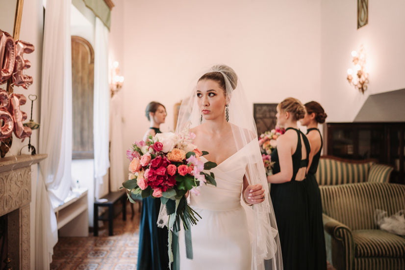 Bride holding flowers, looking aside before wedding. Luxury Wedding at La Badia di Orvieto, riccardopieri