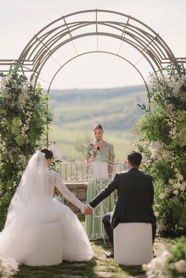 Bride and groom holding hands, officiant speaking at wedding ceremony. wedding at Vignamaggio
