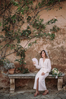 Bride Sara sitting with fan Tuscan garden