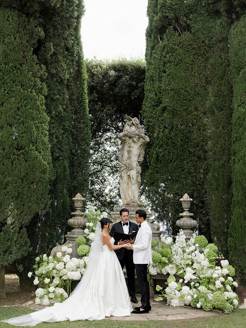 wedding couple standing under floral ceremony setup in Tuscany garden