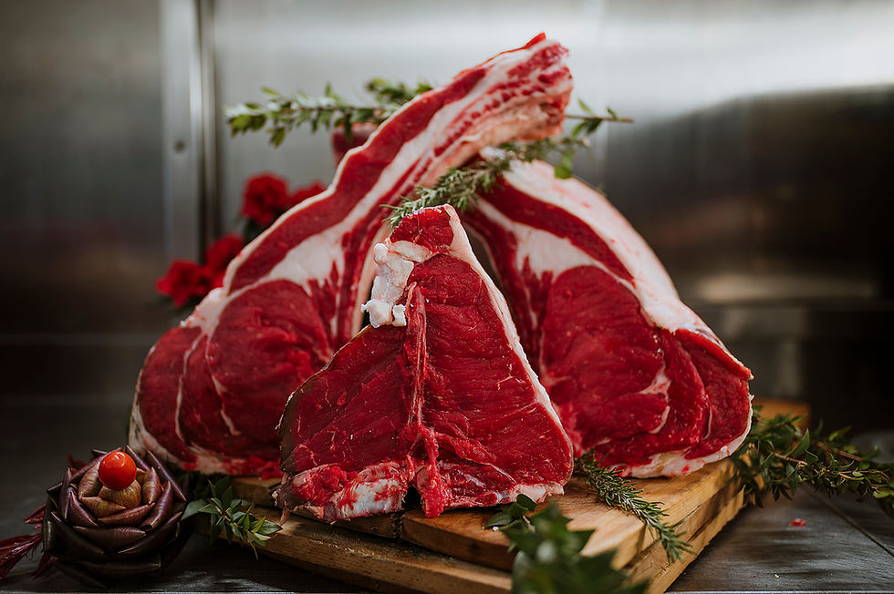 Tomahawk e T-bone crudi su tagliere di legno con erbe