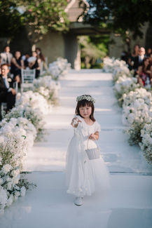 Flower girl in white dress on the aisle, luxury wedding at Ayana Resort Bali