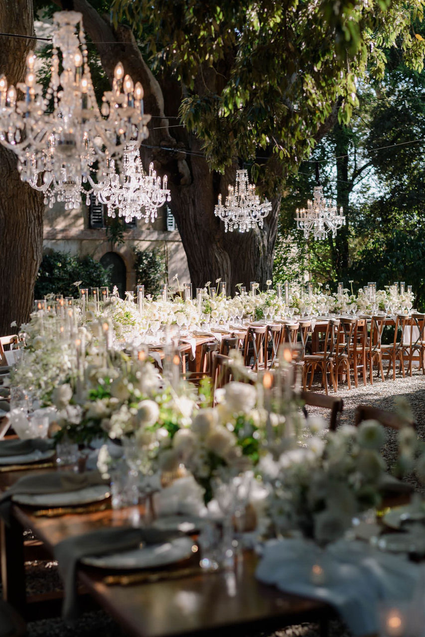 elegant outdoor wedding reception with chandeliers and floral arrangements in Tuscany