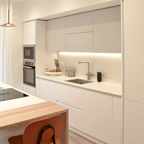 Cucina moderna bianca con penisola in legno e sgabelli.