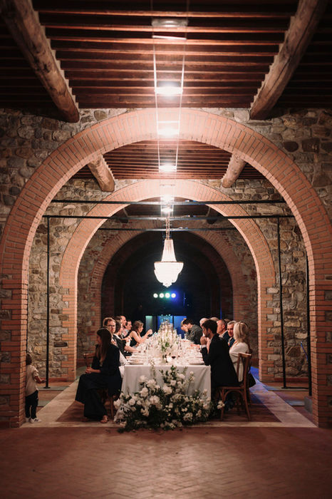 Long wedding reception table with guests in arched cellar, laticastelli wedding photographer.