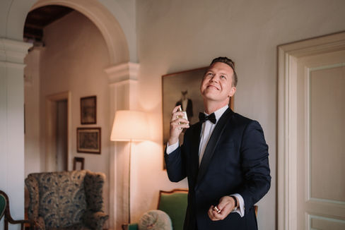 Groom applying perfume in tuxedo.