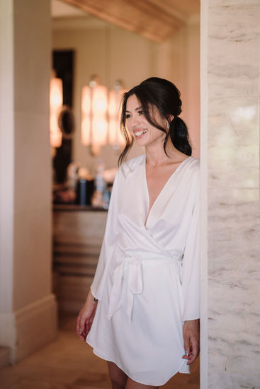 Smiling bride in white robe, hallway background, Anya and Ray – Luxury Wedding at Ayana Resort Bali