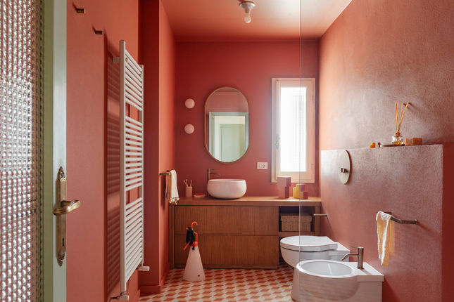 Bagno moderno con pareti color ruggine e lavabo a ciotola.