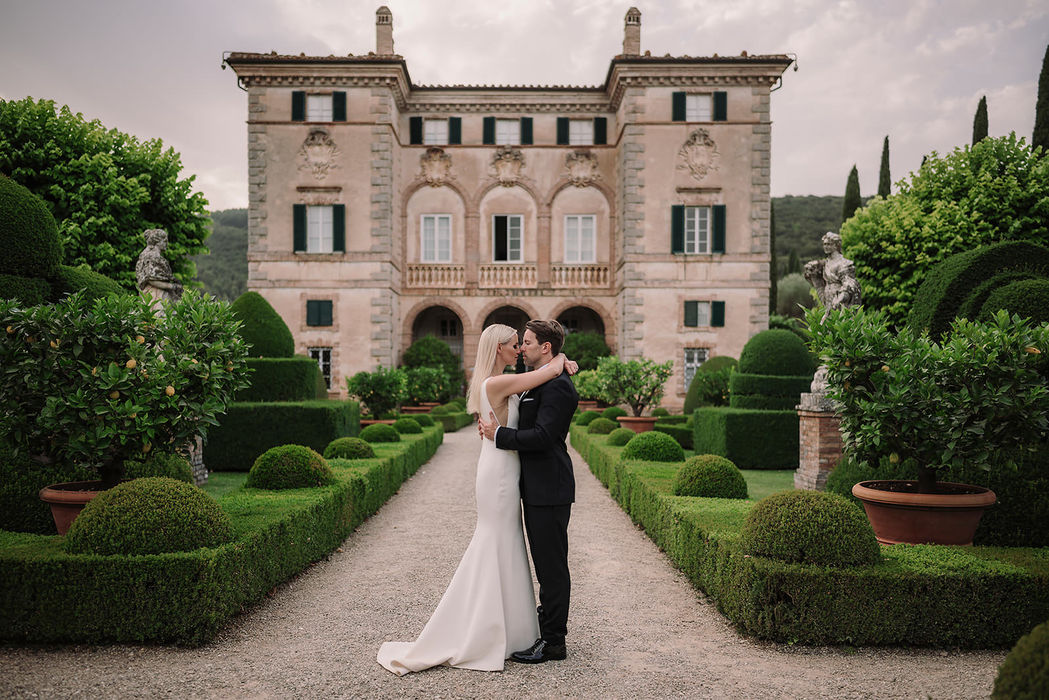 Bride and groom embracing in formal gardens of Villa Cetinale, Tuscany wedding photography
