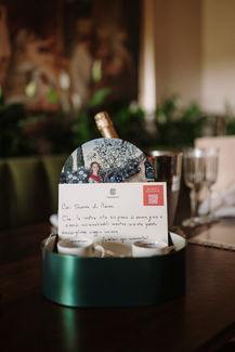 Table setting with card, wine bottle, and greenery, elegant event decor riccardopieri