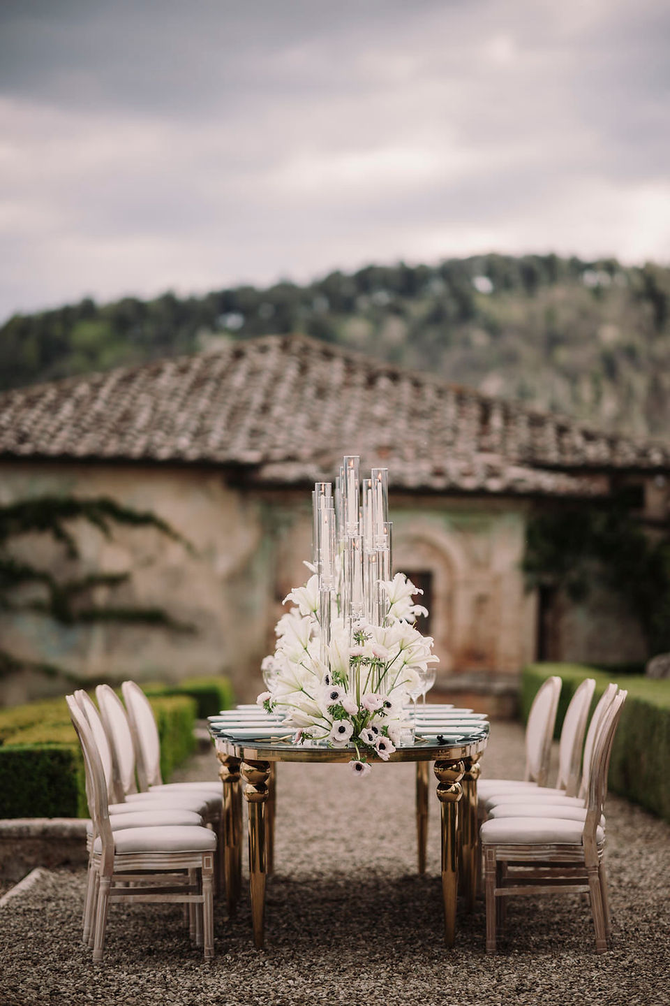 Elegant wedding table with tall candles and white flowers in a historic garden.