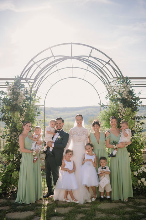 Bride with bridesmaids in sage green dresses under arch at Vignamaggio wedding Tuscany