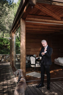 Groom adjusting cufflink, dog watches. Federica and Riccardo – seaside wedding at Borgo dei Santi.