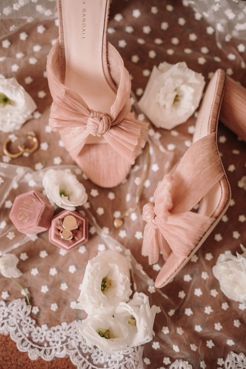 Elegant detail shot of pink bridal shoes with wedding rings and bouquet. Italian destination wedding photographer.