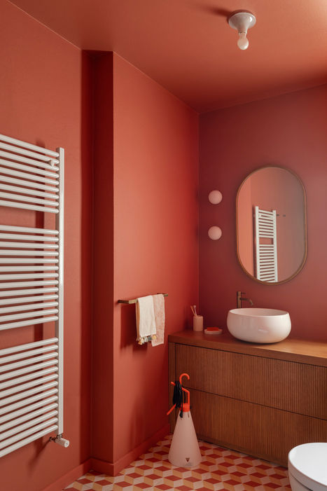Bagno moderno con pareti rosse, lavabo a ciotola e termoarredo.