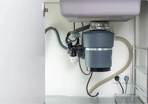Plumber replacing a garbage disposal under a kitchen sink in Bethel Park PA