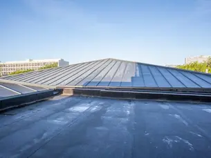 Flat roof membrane damage on a Pittsburgh commercial building showing ponding water and seam separation