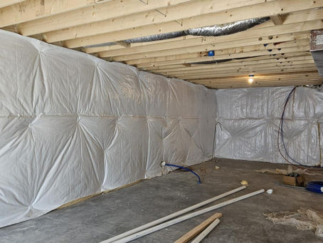 Contractor applying closed-cell spray foam insulation to a wet basement wall in North Huntingdon PA