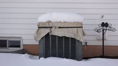 Outdoor air conditioner condenser beside a Somerset, PA home after a winter snowfall