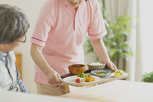Une personne portant un plateau à une personne âgée. 