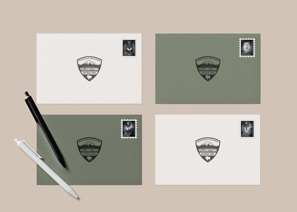 Four envelopes branded with a Yellowstone National Park sticker are arranged on a tan background, each one showing a different wolf stamp in use.