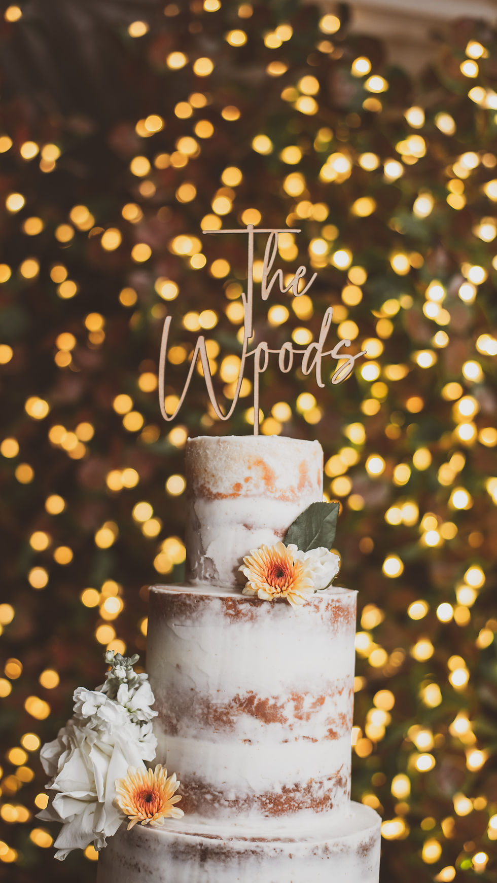 A boho floral cake with a topper on it with uplighting in Danca Del Sol A Wedgewood Winery in temecula