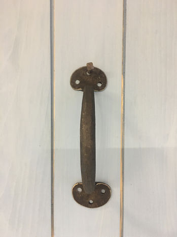 Rustic cast iron door handle on white wood surface