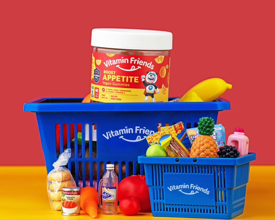 Vitamin container and fresh produce in a blue basket against a red background