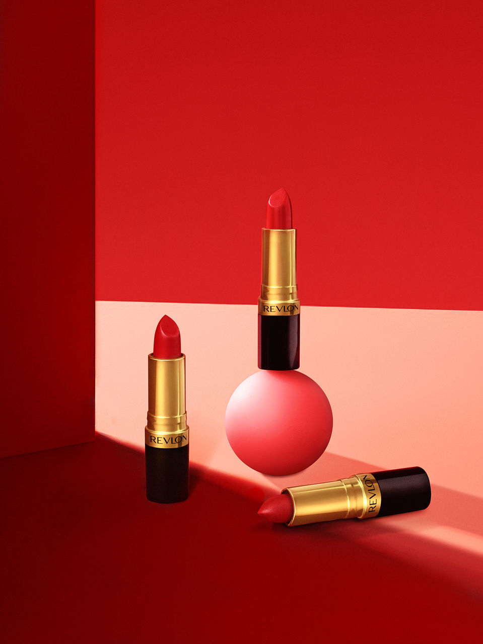  Colorful and dynamic commercial photography featuring a trio of Revlon lipsticks styled against a bold red setting. KV Media Group Dallas.