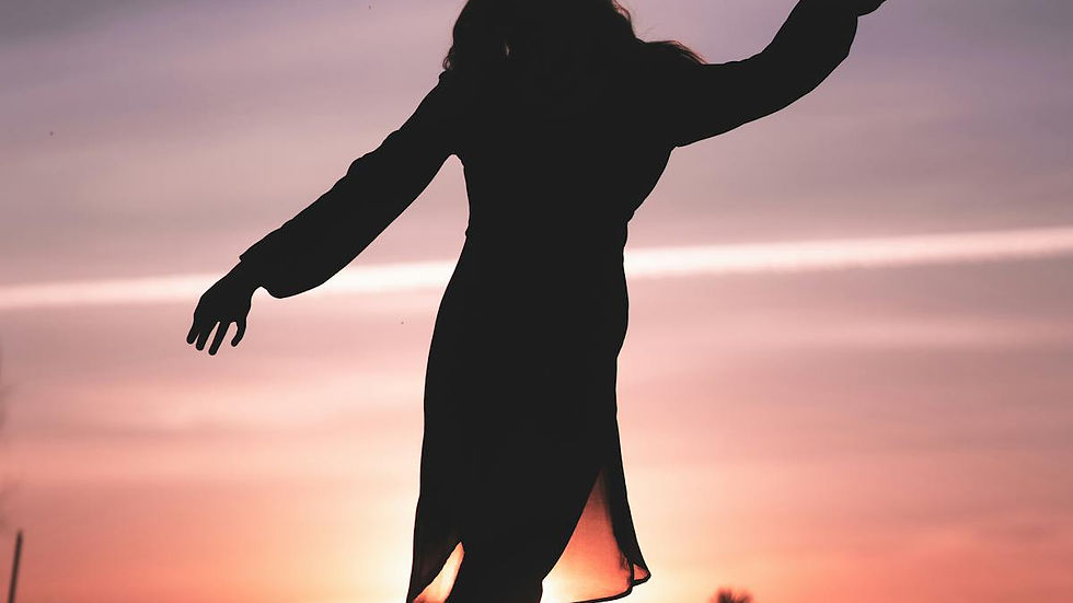 A woman dancing in silhouette at golden sunset — reclaiming her power and golden shadow