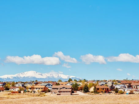 A scenic town featuring houses with mountains rising majestically in the background.