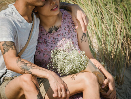 couple with tattoos hugging and holding flowers