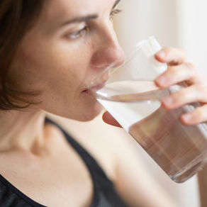 Woman in black tank top drinking water.