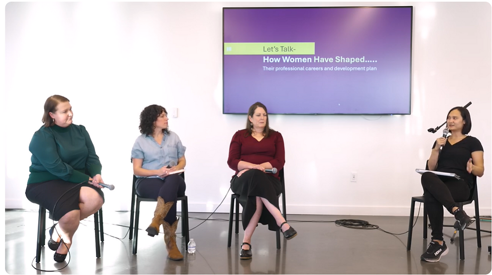 Four women panelists sit on stools with microphones before a screen reading Let’s Talk- How Women Have Shaped... in a bright room