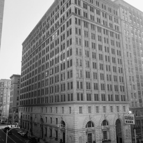 Large historic building with arched windows, street scene with vintage cars and pedestrians. Citizens & Southern Bank sign visible.