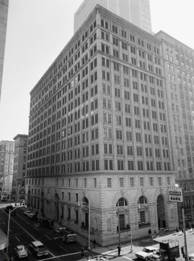 Large historic building with arched windows, street scene with vintage cars and pedestrians. Citizens & Southern Bank sign visible.