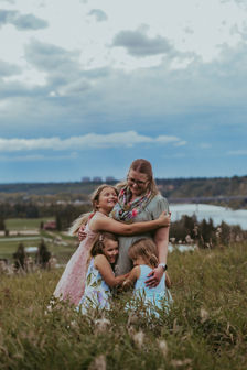 mother with small children posing in a scenic field during a family photoshoot in Edmonton, Alberta.