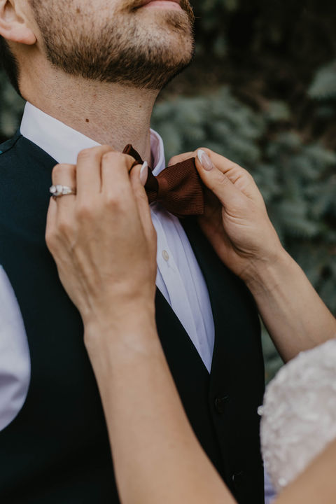 brides hands carefully readjusting her grooms tie 