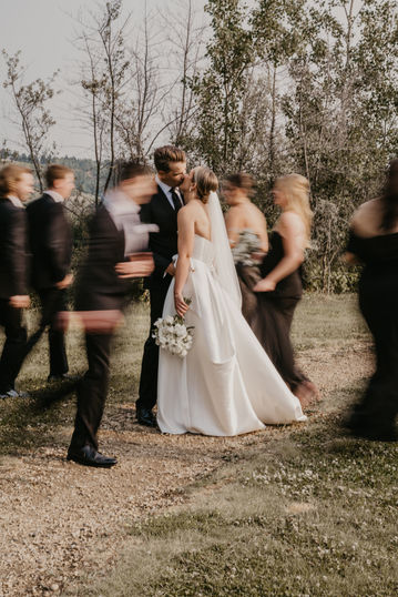 Bride and groom in focus while bridal party runs around them during a wedding portrait session in Edmonton Alberta.