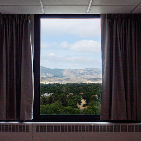 college dormitory empty aside from newly installed blackout drapery that is pleated and a metallic light grey color